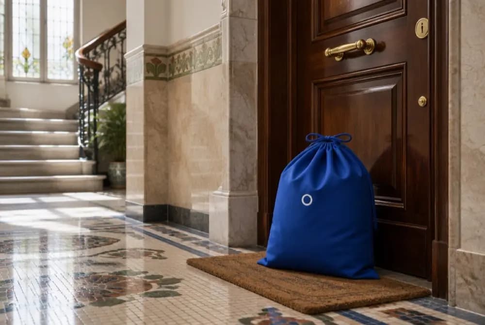 A blue HolaWash bag waiting on a doormat inside a Barcelona entrance hall