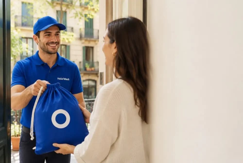 A HolaWash courier handing a blue laundry bag to a customer at her door in Barcelona